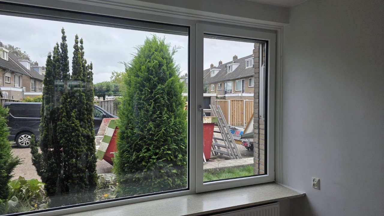 Breed wit kunststof raamkozijn met triple glas en een afgewerkte vensterbank aan de voorzijde in Aalderinkshoek
