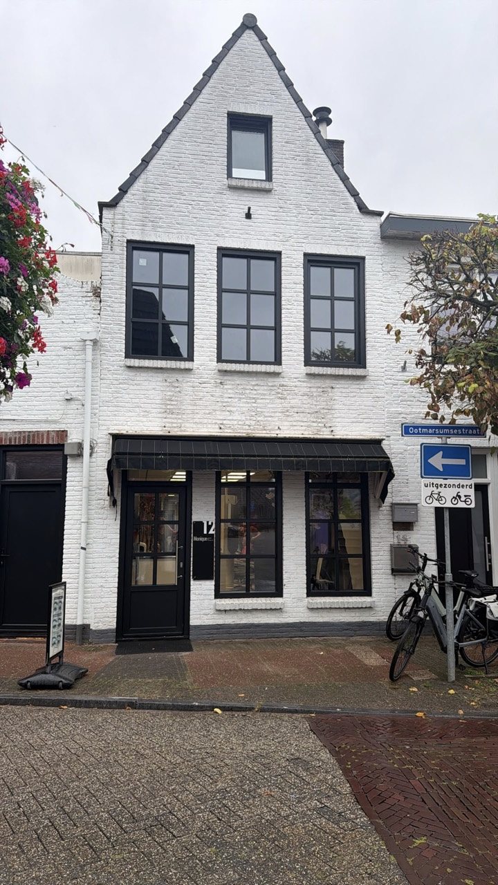Vernieuwde matzwarte kunststof raamkozijnen met roedes in de witte voorgevel van een kapperszaak in Almelo