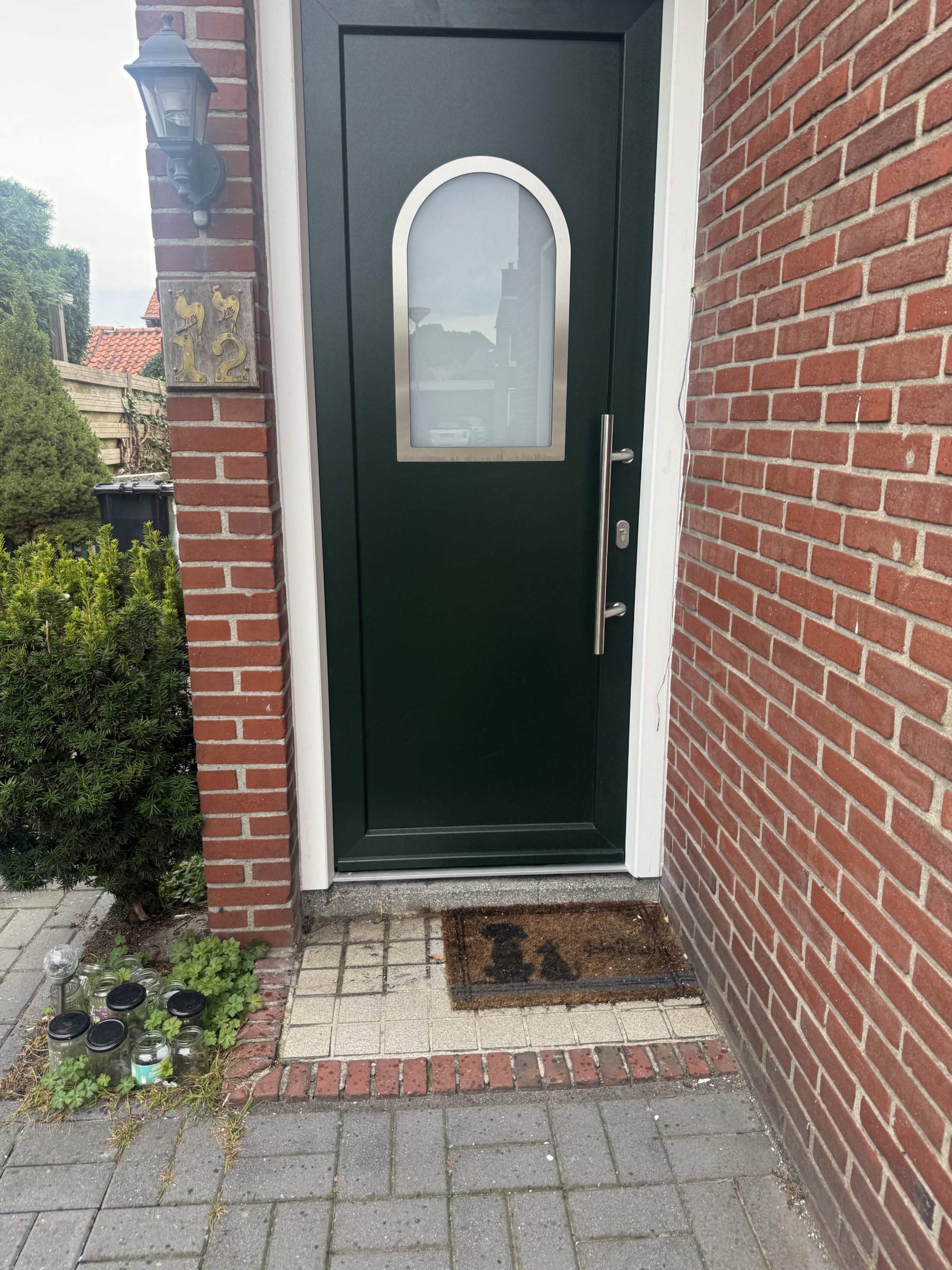 De nieuwe geïsoleerde voordeur, model 22, met boogvormig glasvlak en verticale greep.
